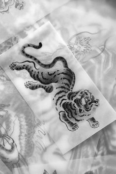 black and white image of a tiger on a bed sheet with dragon designs in the background