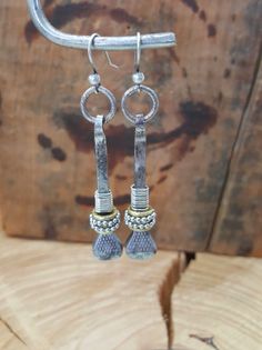 silver and gold earrings hanging from a hook on a piece of wood with a wooden background