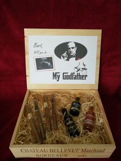 an open wooden box containing four bottles of wine and a note on the label that says, my godfather