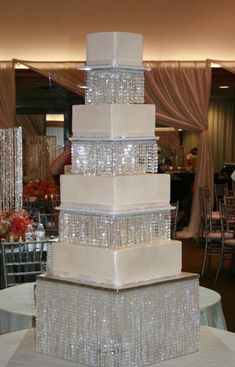 a tall white cake with lots of crystal beads on it's sides and the top tier