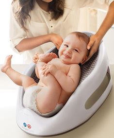 a baby in a bath tub being bathed by a woman