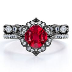 a close up view of a ring with a red stone in the center and white diamonds around it