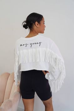 This sweatshirt is the perfect one for brides-to-be and bridal party for a bachelorette party! This cropped sweater has fringe running from arm to arm. Personalize your sleeve with your future last name, wedding date, inside joke or whatever short phrase you desire!  Please read all information down below thoroughly as we do not accept returns, cancellations or exchanges. Message us for any questions you may have prior to purchasing. By purchasing this item you have agreed to all below terms & i White Crew Neck Top For Bridal Shower, Wifey Sweatshirt, Gift Bachelorette Party, Inside Joke, Bachelorette Party Bride, White Fringe, Bachelorette Trip, Fringe Sweater, Big Sis