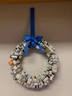 a wreath made out of bottles is hanging on the wall with a blue ribbon around it