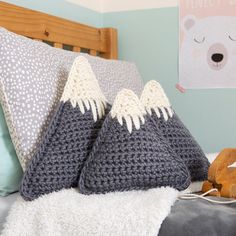 two crocheted pillows sitting on top of a bed next to a wooden sleigh