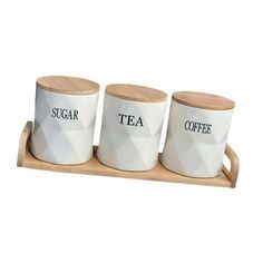 three white ceramic cups with wooden trays on them that say sugar, tea and coffee