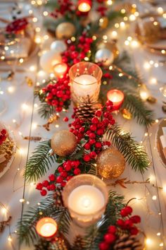 a long table with candles and christmas decorations on it, surrounded by pine cones and red berries