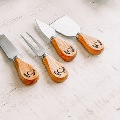 four wooden utensils with carved designs on them sitting next to knives and spatulas