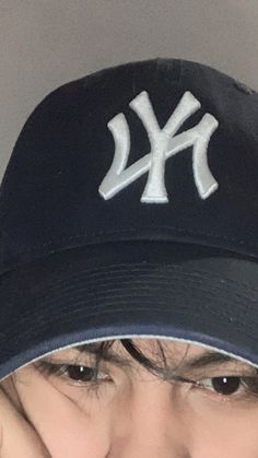 a woman wearing a new york yankees hat and holding her hand up to her face