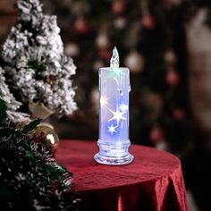 a lighted candle sitting on top of a table next to a christmas tree and decorations