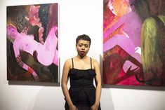 a woman standing in front of two paintings on the wall, one is wearing a black dress