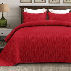 a bed with red comforters and pillows in a room