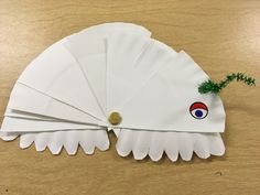 four white paper fan shaped like an eagle with a pine branch sticking out of it