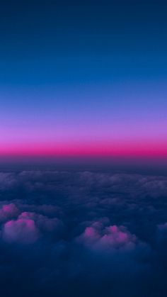 the view from an airplane looking down at some clouds and blue sky with pink hues