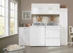 a washer and dryer sitting in a room with white cabinets on the wall