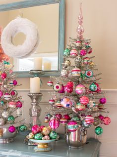 a decorated christmas tree sitting on top of a table next to a mirror and candle