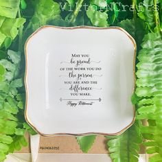 a plate with a quote on it sitting in front of some green plants and leaves