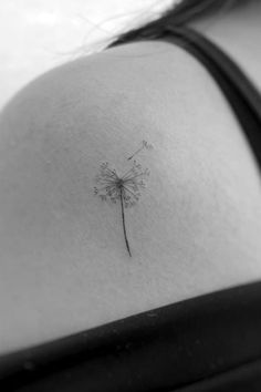 a black and white photo of a woman with a dandelion tattoo on her back