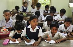 there are many children sitting at desks with notebooks and pencils in front of them