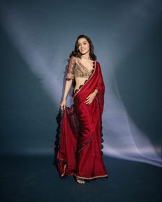 a woman in a red sari is posing for a photo with her hands on her hips