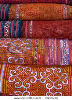 an assortment of colorful hand woven fabrics in different patterns and colors, stacked on top of each other