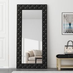 a large black framed mirror sitting on top of a wooden table next to a white couch