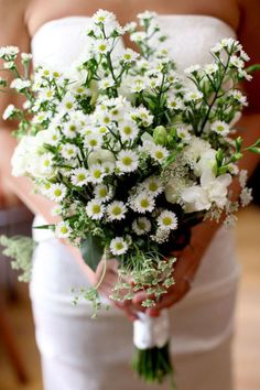 a bride holding a bouquet of white flowers