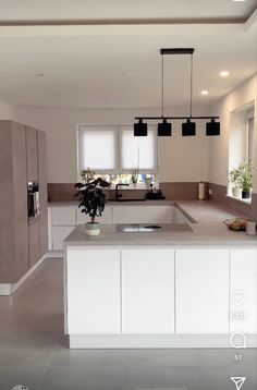 a large kitchen with an island counter top and two lights hanging from it's ceiling