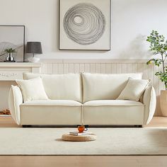 a living room with a white couch and coffee table in front of a painting on the wall