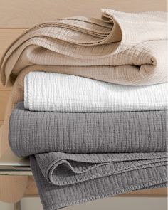 folded towels and blankets are stacked on top of each other