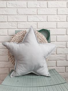 a white star pillow sitting on top of a green table next to a brick wall