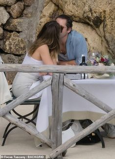 a man and woman kissing in front of a table