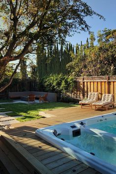 a hot tub sitting on top of a wooden deck next to a lush green field