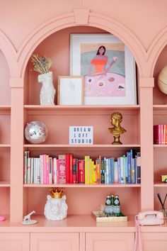 a pink bookcase with lots of books on it