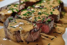 steak with gravy on a plate covered in sauce and garnished with chives