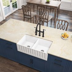 a kitchen with blue cabinets and marble counter tops, two white double - basin sinks