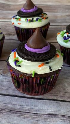 chocolate cupcakes with white frosting and purple icing topped with a witch's hat