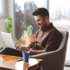 a man sitting in a chair working on his laptop