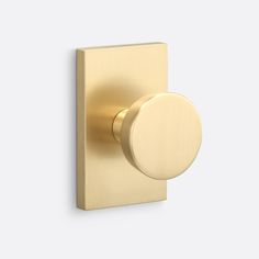 an image of a gold door knob on a white wall with a round button in the middle