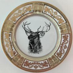 a white and gold plate with an image of a deer's head on it