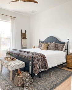 a bedroom with a bed, bench and ceiling fan in the corner next to an open window