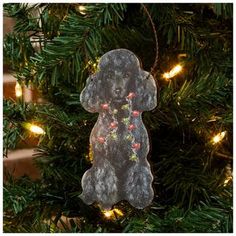 a dog ornament hanging from a christmas tree with lights on it's branches