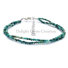 two stranded bracelet with green beads and a silver charm on the clasp, one beaded