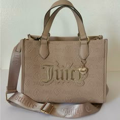 Juicy Couture Upgrade U Mini Tote Condition: New With Tags Color: Cafe * Tan / Cafe Faux Leather W/ Debossed Juicy Logos * Gold Tone Hardware And Front Heart Charm W/ Crystal Accents * Flat Double Carry Handles W/ 5” Drop * Adjustable Crossbody Strap W/ 23” Drop (Not Detachable) * Open Top W/ 1 Zip Pocket And 2 Slip Pockets * Measurements: 9.5”W X 7.75”H X 5.5”D Msrp $99.00 Cafe Gold, Pretty Backpacks, Juicy Couture Clothes, Juicy Bag, Fav Products, Candle Pedestal, Luxury Bags Collection, Juicy Couture Purse, Juicy Couture Accessories