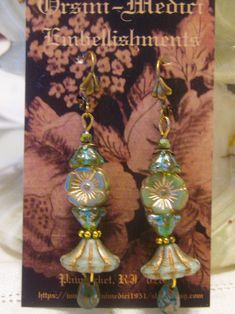 a pair of earrings with glass beads on it's earwires in front of a flowered background