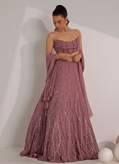 Elevate your style effortlessly with the striking Lilac Embellished Lehenga with Corset Blouse, designed to make a lasting impression. Crafted from luxurious organza, the Lilac flowing lehenga features intricate mix-media embroidery, creating a delicate shimmer with silver embellishments that add an ethereal touch. Paired with a strapless corset blouse offering a flattering fit with minimal embellishment, this outfit strikes the perfect balance between elegance and modernity. Completed with a matching dupatta, this set is ideal for Mehndi, Sangeet ceremonies, or as wedding guest attire. Composition : Lehenga, Blouse and Dupatta - Organza and Shantoon Care: Dry Clean Only and Vacuum Storage This product can be customized for sleeves, blouse length and neckline Delivery : 6-8 weeks as the pr Embellished Lehenga, Blouse Designed, Wedding Guest Attire, Corset Blouse, Vacuum Storage, Lehenga Blouse, Strapless Corset, Guest Attire, Sleeves Blouse