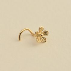 a gold nose ring with a flower design on the front and back of it's ear