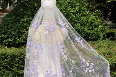 a veil with purple flowers on it is hanging from a mannequin's head