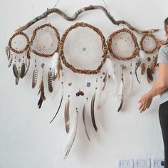 a woman standing next to a wall hanging with dream catchers on it's side