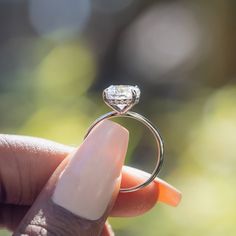 a woman's hand holding an engagement ring with a diamond on the middle finger